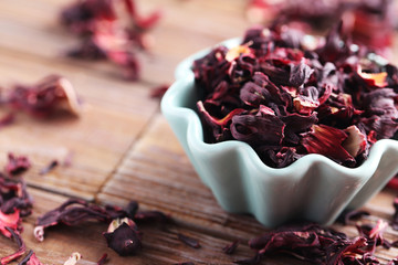 Heap of dry tea with bowl on brown wooden table