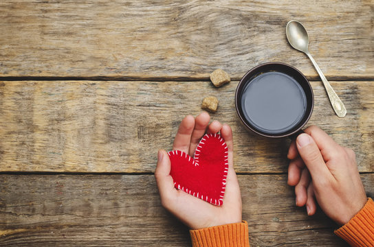 Men's hands hold toy hearts and a cup of coffee for Valentine's