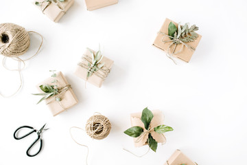 creative arrangement pattern of craft boxes and green branches on white background. flat lay, top view