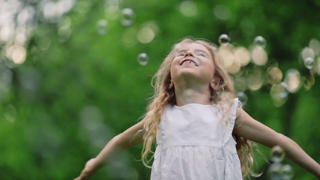 Little girl with soap bubbles in park