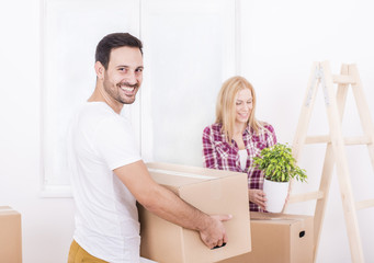 Fototapeta na wymiar Young couple moving in to new home together. Home, people, moving and real estate concept