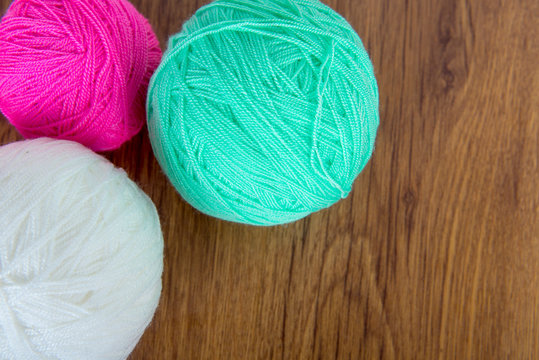 Bright balls of acrylic yarn on a wooden table. Needlework. Knit and Crochet. Fashion trends.