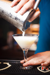 The bartender pours a drink on a cold glass closeup