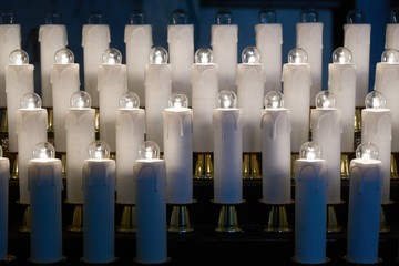 Elektrische Opferkerzen in einem Ständer in einer italienischen Kirche