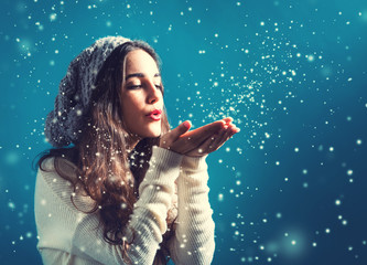 Happy young woman blowing snow