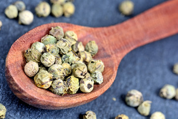 Green peppercorns in a wooden spoon