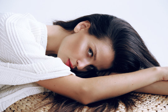 fashion studio photo of beautiful young woman with long dark hair in cozy cardigan 