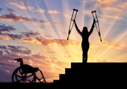 Happy disabled person standing on stairs and holding crutches wheelchair