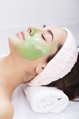 Young woman in a spa with algae facial mask