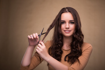 Obraz premium Beautiful woman with scissors cutting her hair