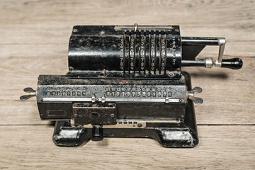 Old rusty retro calculator black standing on a wooden table
