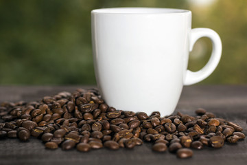 cup of coffee with coffee beans on green bokeh background