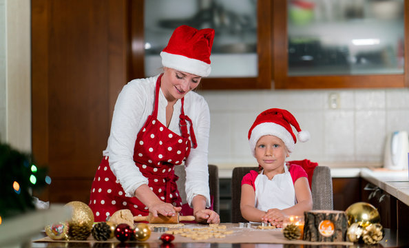 Mother and daughter are preparing gingerbread for Christmas