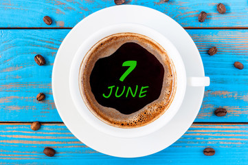June 7th. Day 7 of month, everyday calendar written on morning coffee cup at blue wooden background. Summer concept, Top view