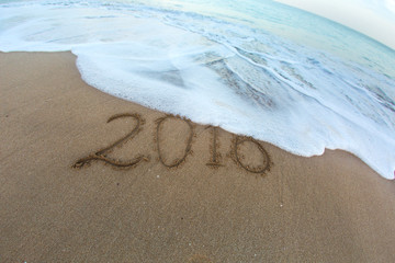 Sea foam flushing out digits 2016 from sand on sandy beach. New