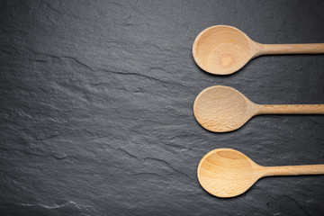black slate board for serving with three wooden spoons, top view