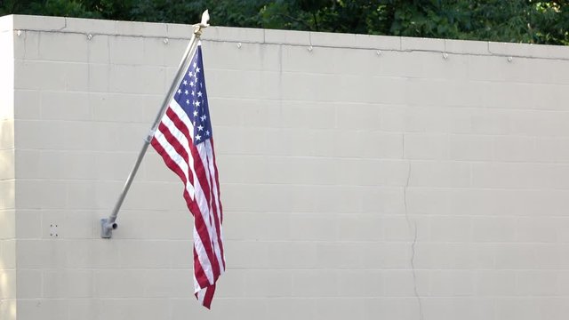 American flag hanging from brick wall, displayed proudly.