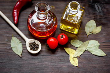 carafes with oil and tomatoes on wooden background