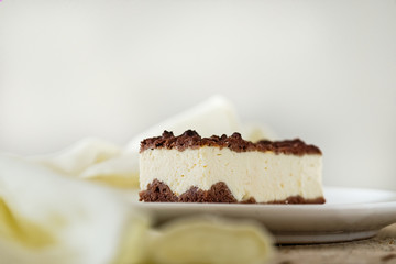 Slice of cheesecake with chocolate crust and chocolate crumble. Wooden background. Horizontal. Light food photography. Free text space.