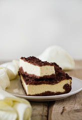 Slice of cheesecake bar with chocolate shortcrust pastry and chocolate crumble. Wooden table. Free text space background. Light food photography