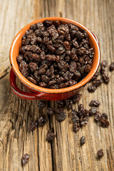 Close-Up Of Raisins In Bowl On wood background