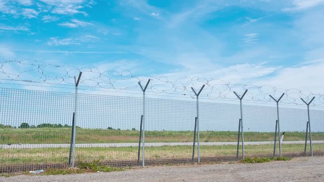 Clouds rushing over barbed wire fence