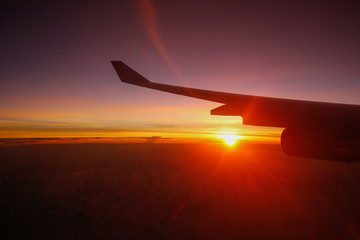 Airplane's wing against golden sunlight in early morning