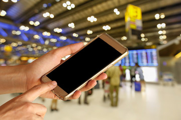 woman hand hold and touch screen smart phone, tablet,cell phone over airport terminal blur background with bokeh light