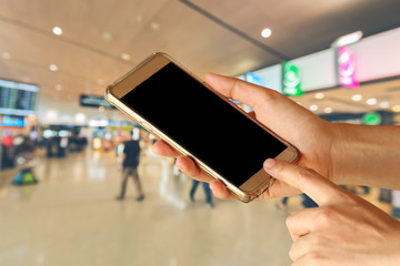 woman hand hold and touch screen smart phone, tablet,cell phone over airport terminal blur background with bokeh light