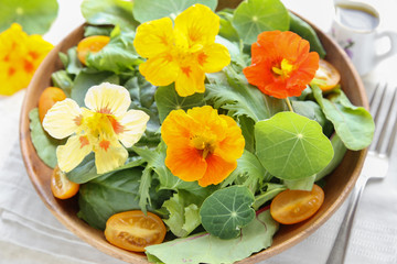 Fresh green salad with edible flowers nasturtium in wooden serving plate, keto, ketogenic, low carb diet, sugar free, dairy free and  gluten free, healthy plant based vegan food