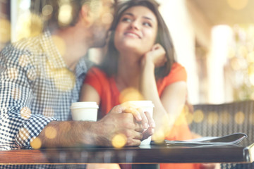 Young couple with drink in cafe. View through window glass effect.