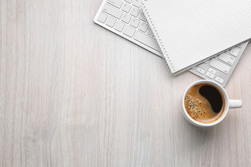 Cup of coffee with office tools on light wooden background