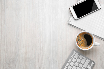 Cup of coffee with office tools on light wooden background