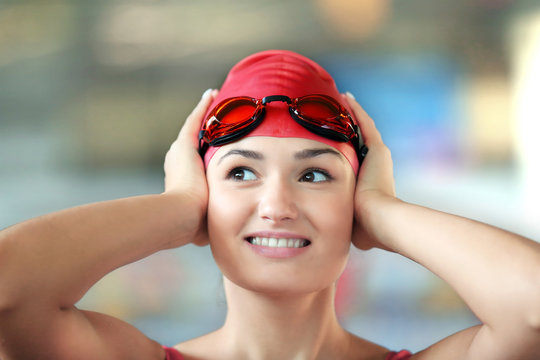 Beautiful girl wearing goggles in swimming pool, closeup
