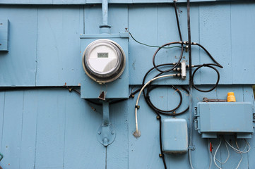 old electric meter installed on the wall of house exterior