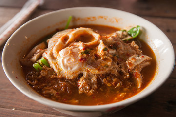 Hot and spicy noodle egg with soup on the wooden table 
