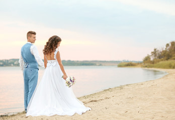 Fototapeta na wymiar Beautiful wedding couple walking along riverside