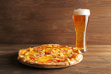 Tasty pizza with beer on wooden table