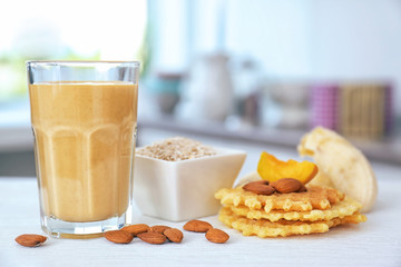 Glass with tasty smoothie, fruits and wafers on kitchen table