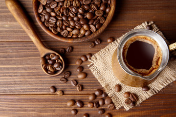 Coffee beans with cezve on wooden background