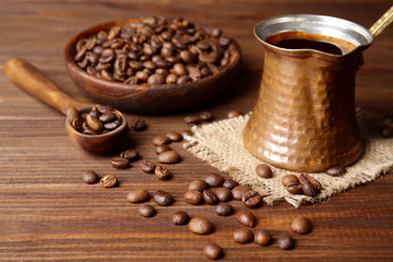 Coffee beans with cezve on wooden background