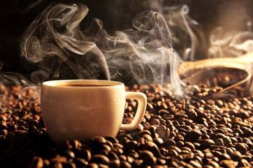 Roasted coffee beans with cup on dark background