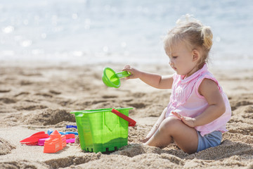 little girl playing sand toys at the beach