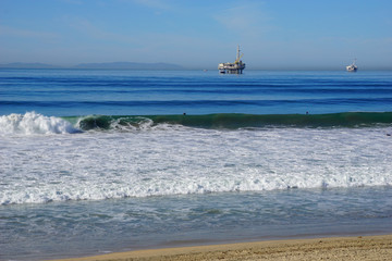 oil platform and surfers in ocean