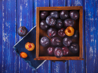 Plums in wooden box on vintage blue background.selective focus.