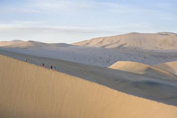 Tourists climb sand dunes in Dunhuang