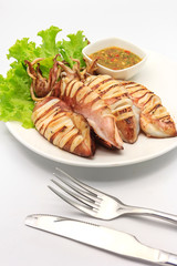 grilled squid serve with Thai hot and spicy seafood, fresh Lettuce and Cutlery Set in white plate on a white background, Top view with copy space and text