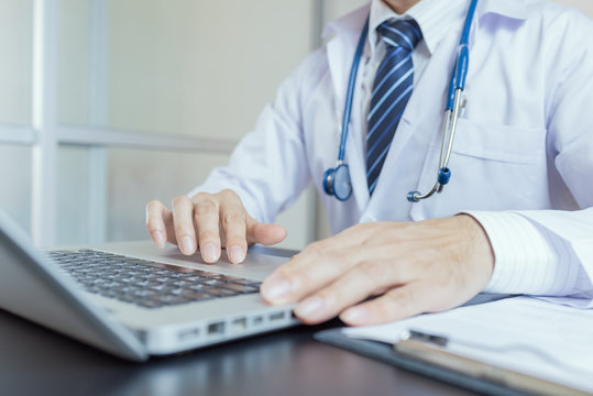 Close-up of a medical worker typing on laptop..