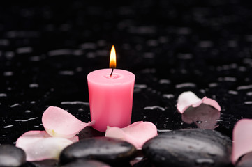 Pink rose petals with two white candle and therapy stones 