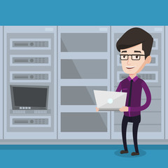 Engineer working on laptop in network server room.